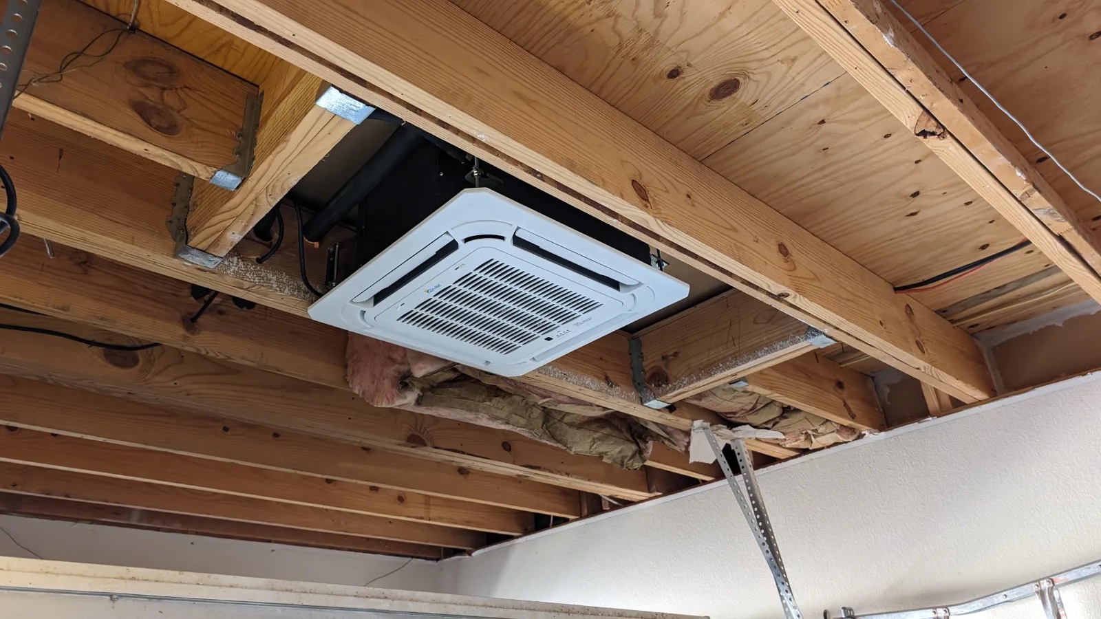 DIY ceiling cassette mini split: four-way recessed cassette installed between framed ceiling joists during a DIY install