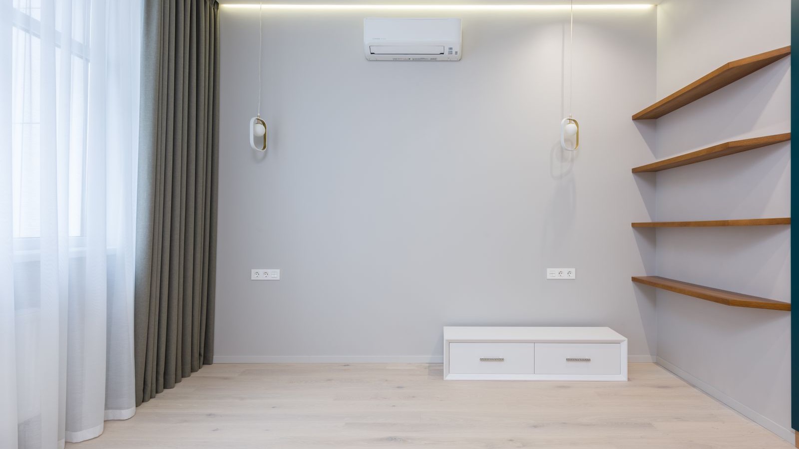 White ductless wall unit mounted high on a pale gray wall in an empty modern room, the kind of single-zone install weighed in this MRCOOL versus Senville DIY comparison